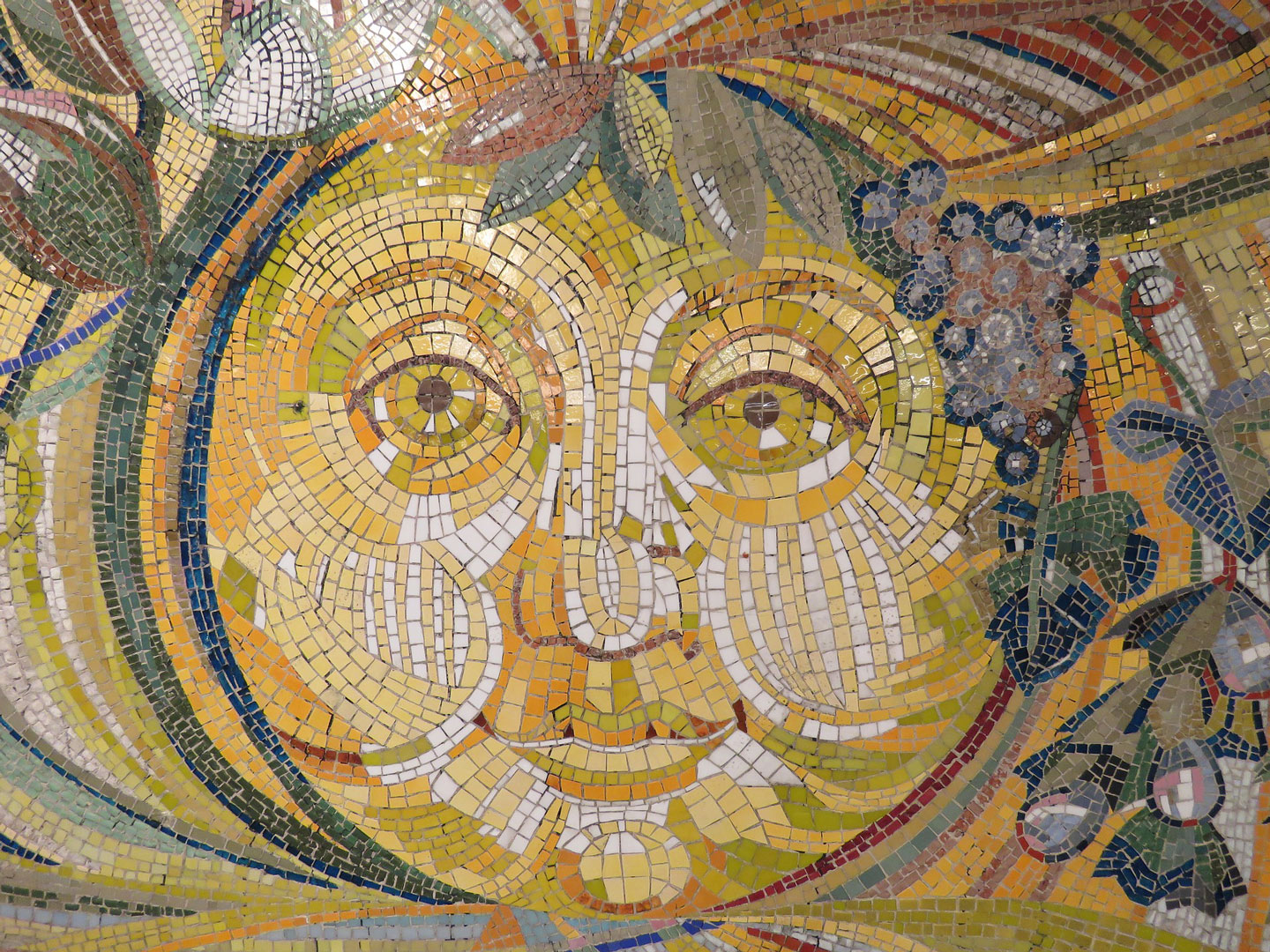 Photo of a mosaic artwork representing an animist Sun with a face